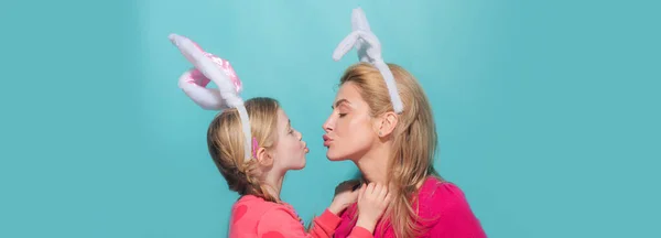 Bonne famille se préparant pour Pâques. Petite fille mignonne et maman portant des oreilles de lapin. Mère et fille s'embrassent. Bannière de Pâques avec espace de copie. — Photo