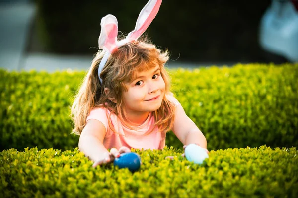 Chłopak polujący na wielkanocne jaja. Chłopiec z wielkanocnymi jajami i króliczymi uszami na świeżym powietrzu. słodkie dziecko mając szczęśliwy Wielkanoc w park. — Zdjęcie stockowe