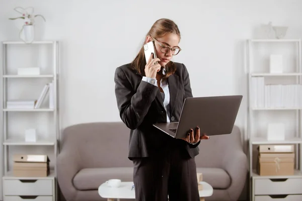Piękna kobieta rozmawiająca przez telefon w kreatywnym biurze. Bizneswoman wewnątrz biura przy użyciu laptopa w biurze. — Zdjęcie stockowe