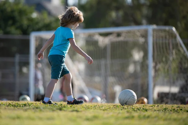 Chłopiec gra w futbol na boisku. Dzieciak gra w piłkę. Aktywne gry w piłkę. — Zdjęcie stockowe