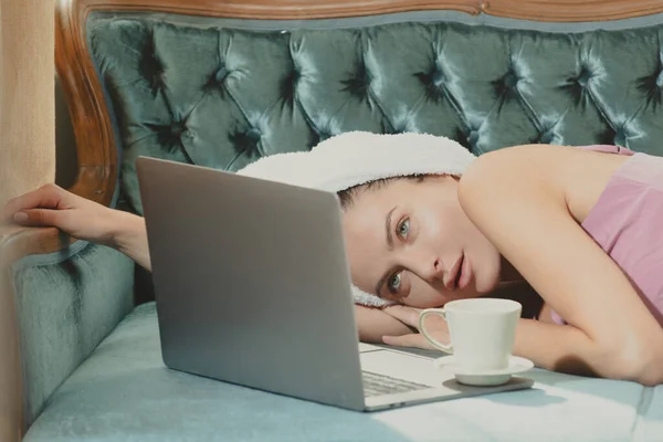 Belle donne in accappatoi e asciugamani con caffè e laptop in camera da letto dopo il risveglio. Modelli spensierati sexy sul letto in appartamento o in camera d'albergo. — Foto Stock