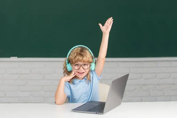 Retrato de menino alegre atraente com a mão levantada usando laptop. — Fotografia de Stock