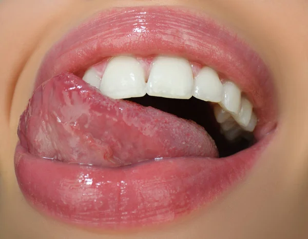 Dental care, healthy teeth and smile, white teeth in mouth. Closeup of smile with white healthy teeth. Open mouth, tongue touches the teeth.
