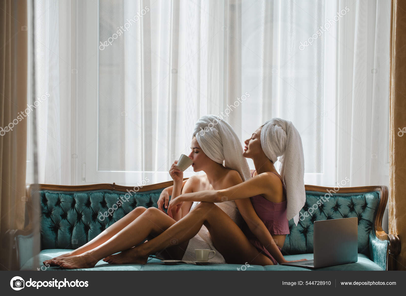 Loving lesbian couple girls drinking coffee embrace on bed. Sexy girlfriends in love at home spend morning together pic