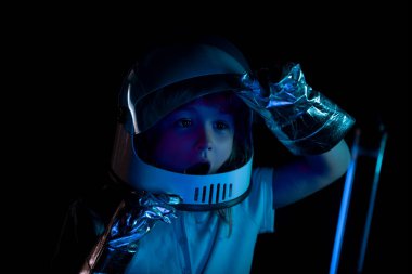 Miğferi rüya gibi görünen küçük astronotun yakın plan yüzü. Kopya alanı ile izole edilmiş arkaplan. Heyecanlı çocukların yüzlerini neon rengine yakın tut.