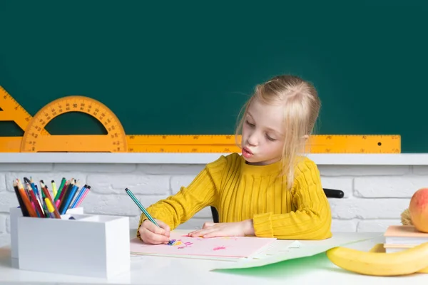 テーブルに座って試験の準備をしている賢いブロンドの女子高生。天才児、知識の日。子供の教育と知識. — ストック写真