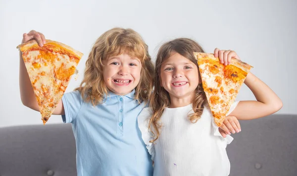 Niños comiendo pizza. Niños felices y emocionados comiendo pizza y divirtiéndose juntos. Niños felices sosteniendo rebanada de pizza cerca de la cara. — Foto de Stock