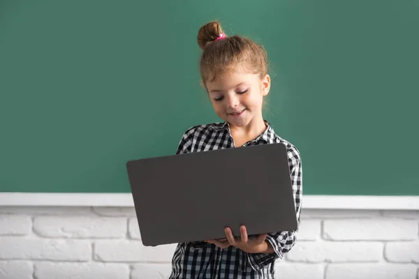 Κορίτσι παιδί χρησιμοποιώντας ένα φορητό υπολογιστή στο σχολείο κοντά μαυροπίνακα. — Φωτογραφία Αρχείου