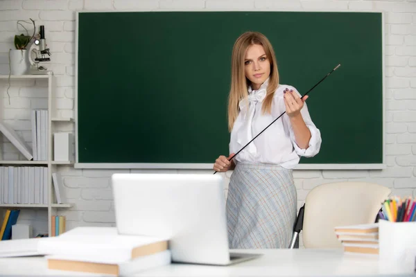 Young teacher with pointer on blackboard with copy space. Portrait of cute attractive young woman student in university or high school college. — Stock Photo, Image
