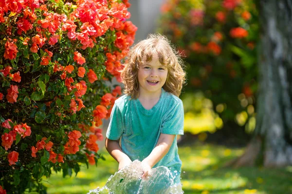 Funny kid have fun and happy smiling on nature backyard. Watering plants in the garden at home on summer day. — Stock Photo, Image