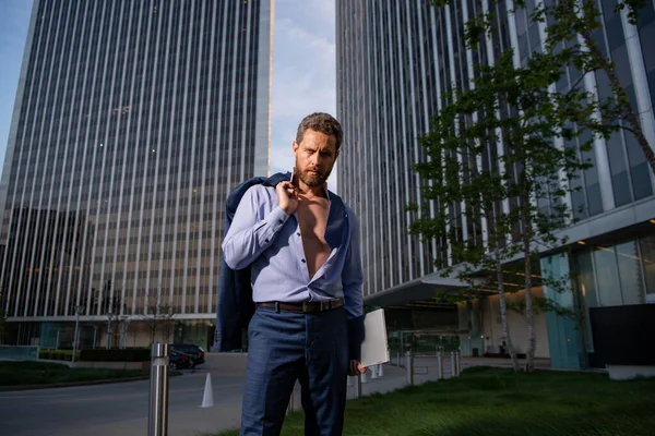 Um homem atraente de camisa. Homem de negócios sexy ao ar livre. Um homem atraente a tirar a camisa. Confiante no seu apelo. Bonito homem modelo de moda. — Fotografia de Stock