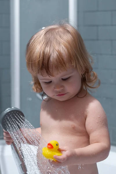 En liten unge som badar i tvålar. Det lilla barnet tvättar håret i badkaret.. — Stockfoto