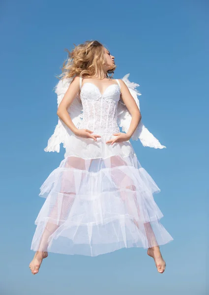 Ángel volador de San Valentín. Chica Cupida con alas blancas. Mujer con alas de ángel con arco y flecha contra el cielo azul. — Foto de Stock