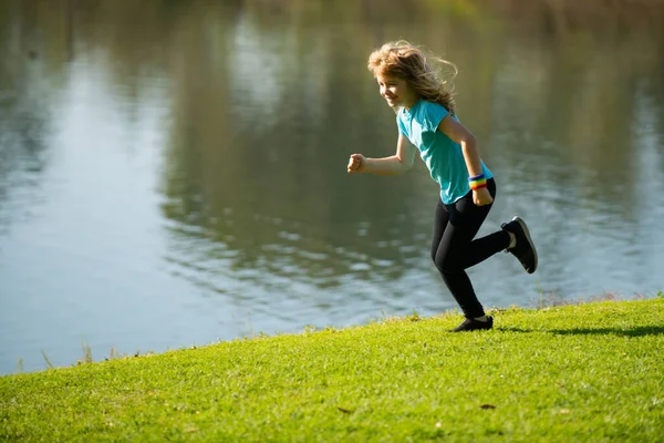 Barn joggar i parken utomhus. Friska sportaktiviteter för barn. En liten pojke på friidrottstävlingen. Ung idrottsman i träning. Utomhus sport och fitness för barn. Kör rörelse. — Stockfoto