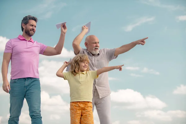 Drei Generationen im Alter von Großvater Vater und Kind Sohn spielen mit Spielzeugflugzeug im Freien. Reisekonzept. — Stockfoto