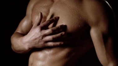 Güçlü atletik erkek fitness modeli karın kaslarını gösteriyor. Siyah arka planda çıplak erkek gövdesi..