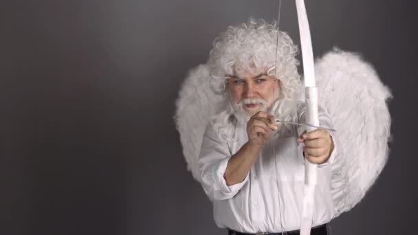 Funny cupid, handsome guy on valentine day with bow arrow shooting. Love concept. Handsome crazy fun angel. Bearded valentin man with angel wings. — Stock Video