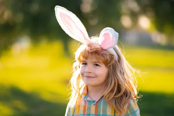 Cara de niño conejito. Niño cazando huevos de Pascua. Niño en orejas de conejo caza huevos de Pascua. — Foto de Stock