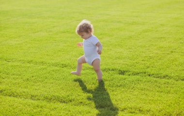 İlk adım. Yeşil çimlerin üzerinde duran bebek çıplak bacakları. Sağlıklı çocuk.