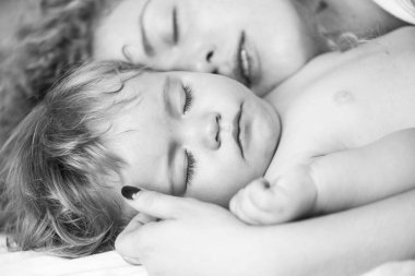 Anne ve bebek yatakta uyuyor. Yatak odasında aile sabahı. Yüzleri kapat.