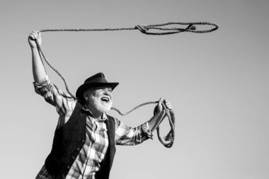 Çiftlikte ya da rodeoda kementi olan yaşlı bir kovboy. Kahverengi ceketli, şapkalı, at ya da inek yakalayan sakallı batılı adam..