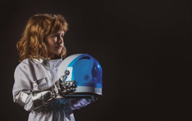 Uzay kıyafetli küçük astronot çocuk elinde siyah kaskla.