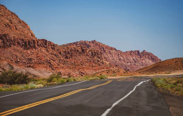 Pouštní dálnice při západu slunce, koncept cestování, USA. Krajina s oranžovými skálami, obloha s mraky a asfaltová cesta v létě. Americký road trip. — Stock fotografie