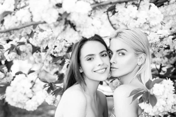 Girls in in cherry sakura blossoms flowers. Outdoor closeup portrait of young beautiful sensual fashion girls posing near blooming tree with pink flowers. — Stock Photo, Image