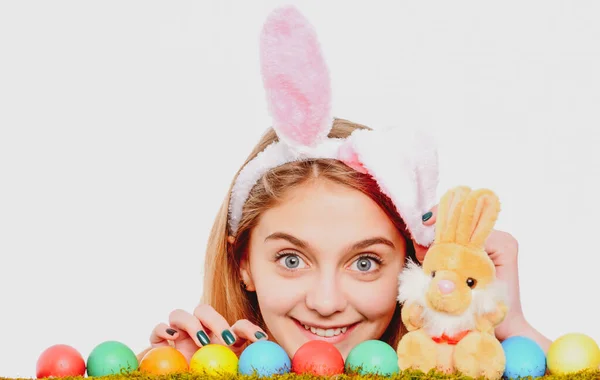 Κυνήγι αυγών. Κορίτσι στα αυτιά κουνελιού του Πάσχα με αυγά. Γυναίκα κρυφοκοιτάζει πάνω από μια επιφάνεια. — Φωτογραφία Αρχείου