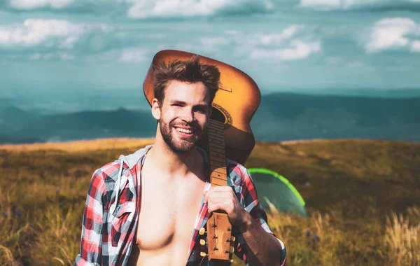 Homem feliz com guitarra no acampamento. Sentindo-se livre e relaxado. Caminhadas de aventura. Homens com guitarra em camisa quadriculada. — Fotografia de Stock