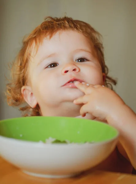 Glückliches Baby, das sich selbst mit einem Löffel isst. Gesunde Ernährung für Kinder. Familie, Essen, Kind, Essen und Elternschaft. — Stockfoto