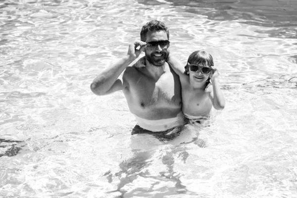 Vader en zoon zwemmen in zwembad, zomervakantie met het gezin. Zwembadfeest. Kind met papa spelen in het zwembad. — Stockfoto