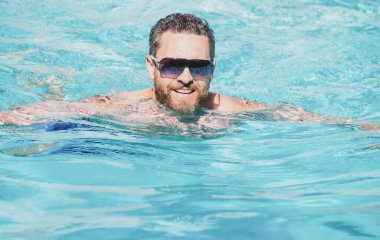 Havuz tatili. Yaz tatilinde yakışıklı bir adam. Güneş gözlüklü adam yüzme havuzunda dinleniyor..
