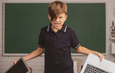 Karşı mesafe eğitiminde kızgın çocuk. Okullu çocuk internetteki bilgisayarı kırdı. Hasarlı bilgisayar teknolojisini parçalamak. Sınıfta uzaktan öğrenmeyle ilgili çocuk problemi.