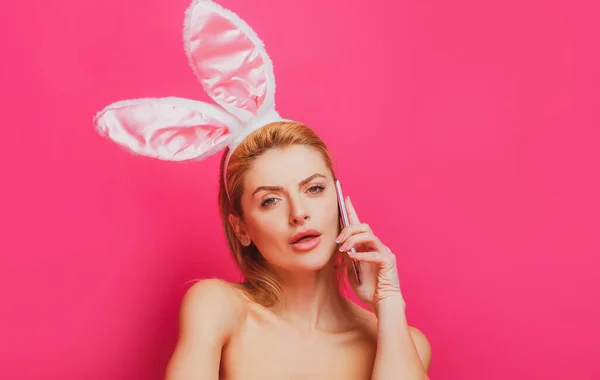 Mujer de Pascua con orejas de conejo hablando por teléfono, aislado en rosa. —  Fotos de Stock