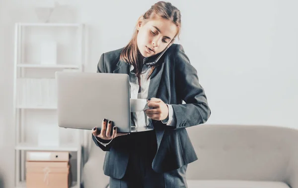 Empresaria sentarse en el interior de la oficina utilizando ordenador portátil en la oficina. Trabajador de oficina ocupado bebiendo café, hablando por teléfono, usando computadora portátil. — Foto de Stock