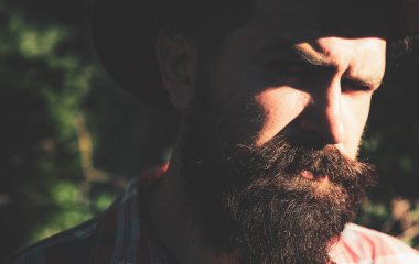 Uzun sakallı, bıyıklı ve son moda saçlı yakışıklı bir adam. Ciddi konsantre erkek modeli..