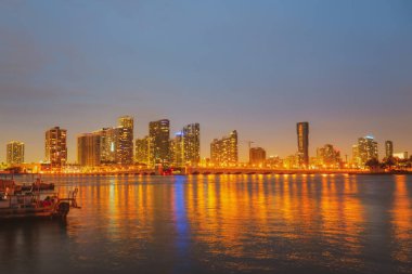 Miami, Florida şehir merkezi Biscayne Körfezi 'nde. Günbatımında şehir gökdelenleri ile Panorama ve yansıma ile deniz üzerinde köprü.