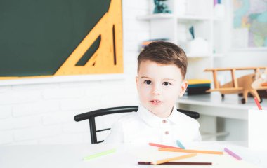 İlkokul öğrencileri. Şirin çocuk içeride bir masada oturuyor..