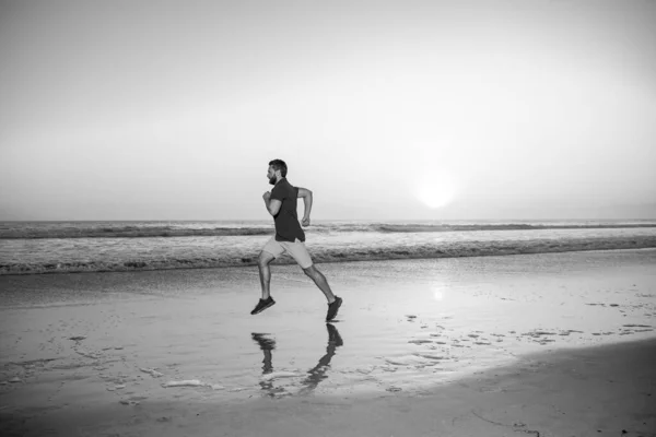 Hombre corriendo en la playa tropical al atardecer. Longitud completa del hombre sano corriendo y corriendo al aire libre. Corredor masculino. Deporte y estilo de vida saludable. —  Fotos de Stock