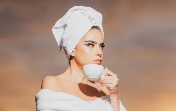 Attraente donna sexy in possesso di una tazza di caffè e guardando l'alba. Bellezza donna con asciugamano sulla testa odore di caffè nella notte al cielo drammatico all'aperto. Mattina spa. — Foto Stock