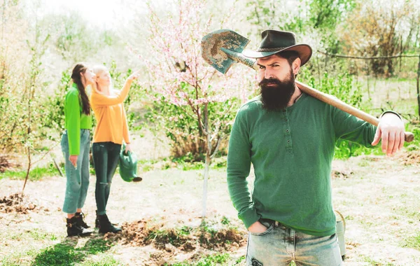 Grupo de trabajo juvenil en patio de primavera con herramientas de jardín. Un grupo de amigos disfrutan de la naturaleza primaveral y cuidan las plantas . — Foto de Stock