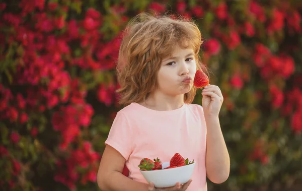 Kinderen met een grappig gezicht. Gelukkig jongetje eet aardbeien. — Stockfoto