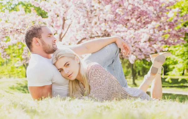 Junges verliebtes Paar. Zwei Menschen entspannen sich in Sakura-Blumen. Romantische Beziehung zwischen Mann und Frau. — Stockfoto