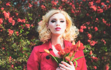 Çiçekli kırmızı elbiseli güzel kız. Çiçekli laleler, bahar çiçekli arka planda..