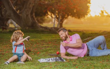Baba oğul güneşli parkta satranç oynuyorlar..