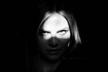 Siyah arka planda ışığı olan şehvetli bir kadın. Karanlıkta güzel bir kadın yüzü. Ciddi bir bakış. Moda sanat stüdyosu portresi. Yaratıcı portreler. Gölgeli ve kadınlarda ışık. Gözleri ışıkta..