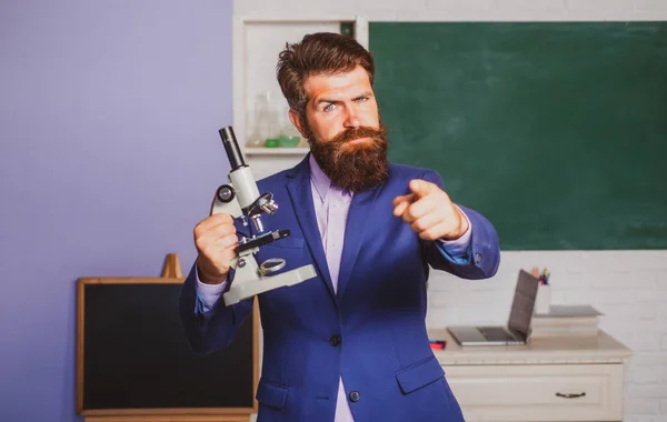 Учитель бородатый человек с ноутбуком, имеющий идею, указывающий пальцем на тебя. Удивленный учитель ждет учеников, уверенно улыбаясь. — стоковое фото