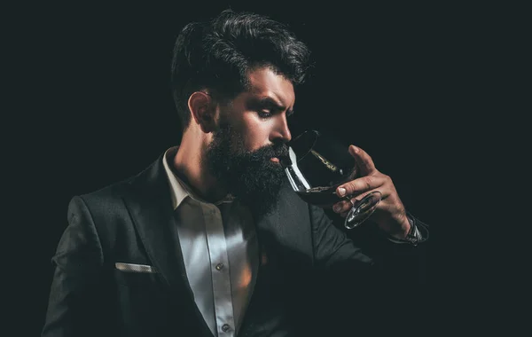 Fröhlicher bärtiger Mann trinkt teuren Cognac. Altes traditionelles Whiskeygetränk - Gentlemen Drink. Eleganter und stilvoller Mann in klassischer Kleidung mit Glas und Cognac in der Hand. — Stockfoto