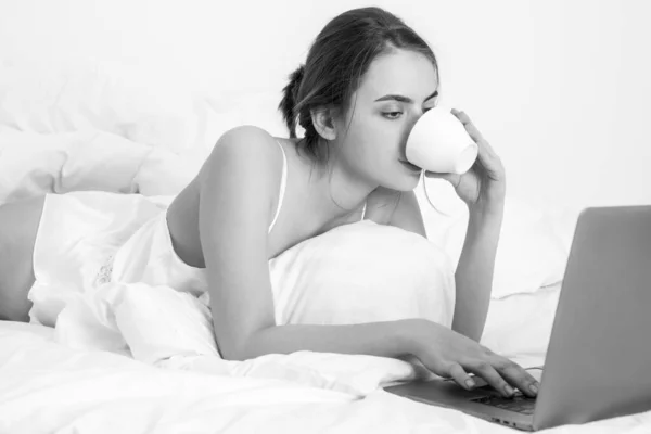 Giovane donna che si diverte a letto sul soggiorno con caffè e laptop. — Foto Stock